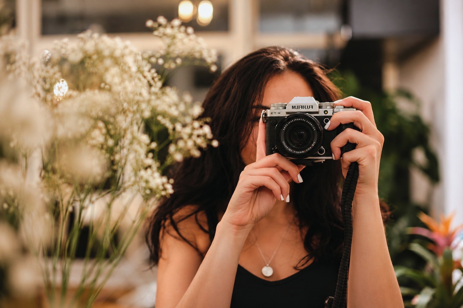Fotografin hält ihre Kamera vor weiße Blüten