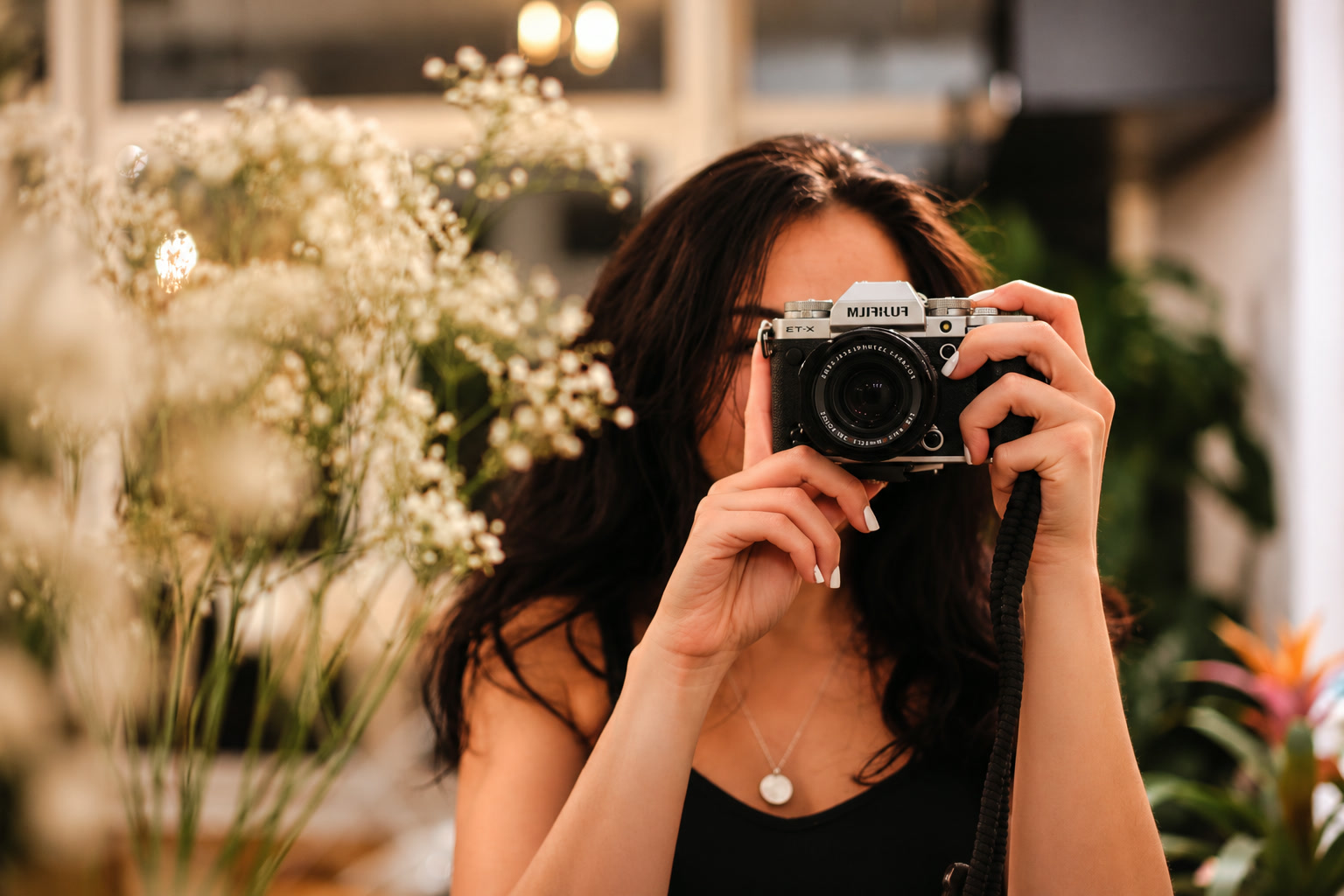 Fotografin hält ihre Kamera vor weiße Blüten